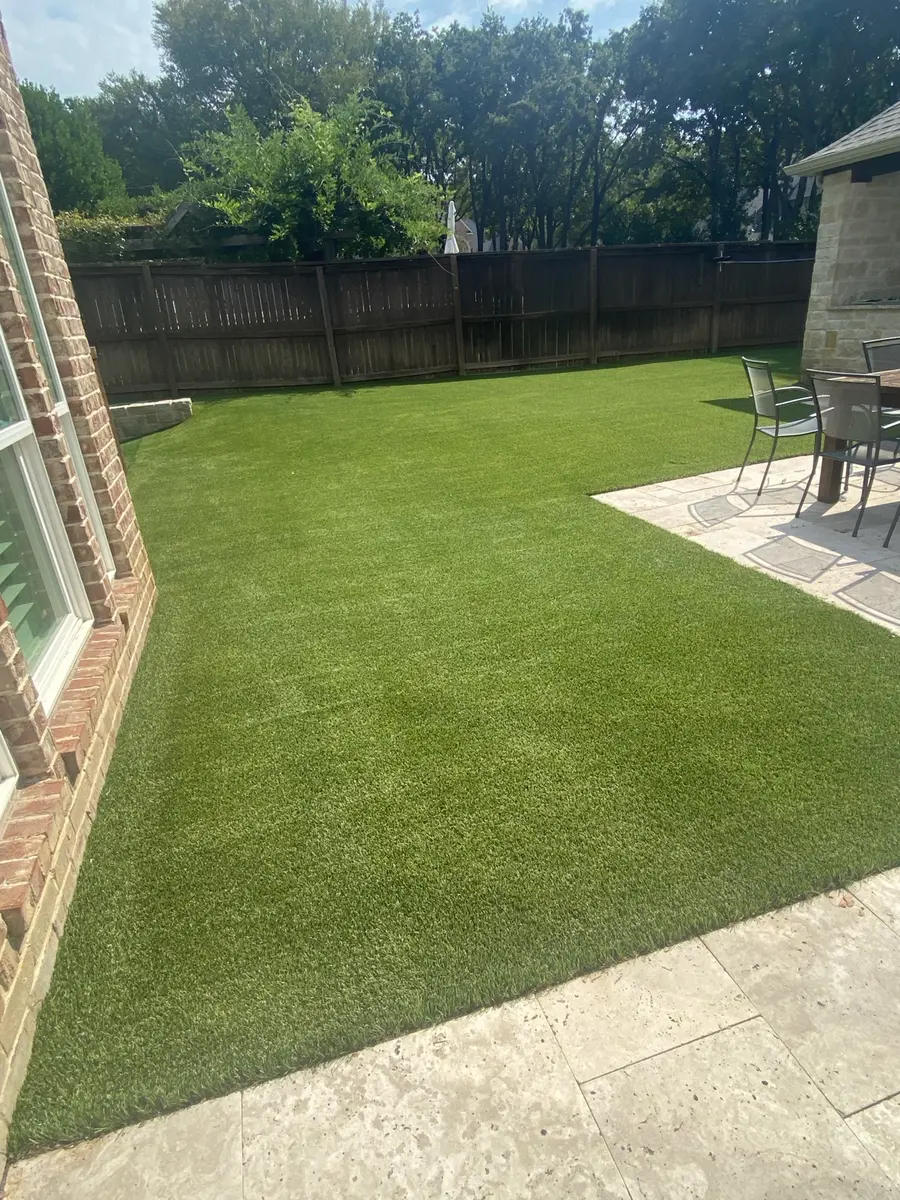 Residential artificial turf beside a patio after professional cleaning