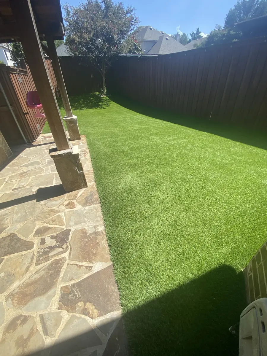 Finished artificial turf beside a residential stone patio