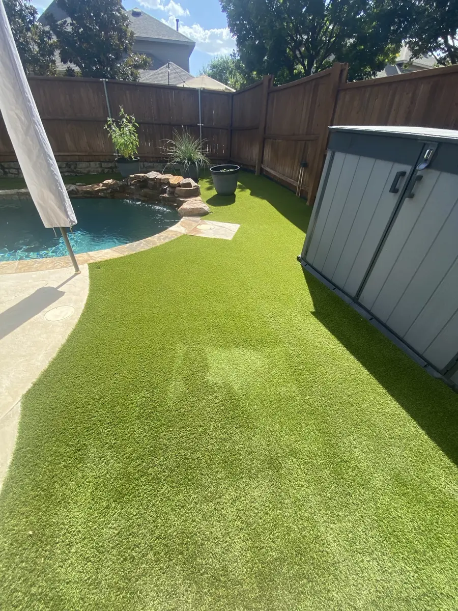 Completed artificial turf cleaning beside a residential pool and storage area
